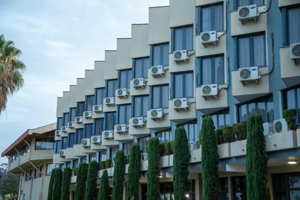 Exterior view of a hotel building featuring rows of windows and air conditioning units, against a clear sky.